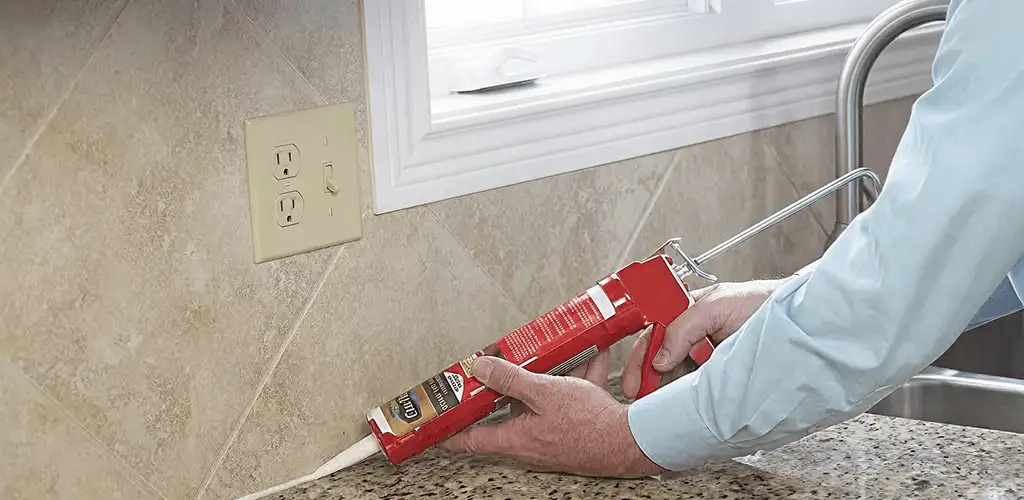Handyman applying caulk along a kitchen backsplash and countertop seam in Evansville, IN