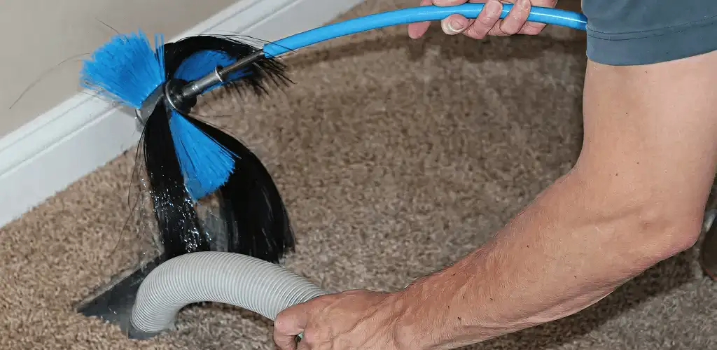Dryer vent cleaning technician brushing lint from a vent line in Evansville, IN