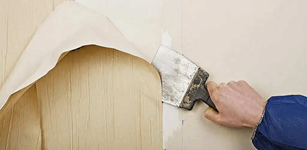 Handyman removing wallpaper with a scraper for wall preparation in Evansville, IN