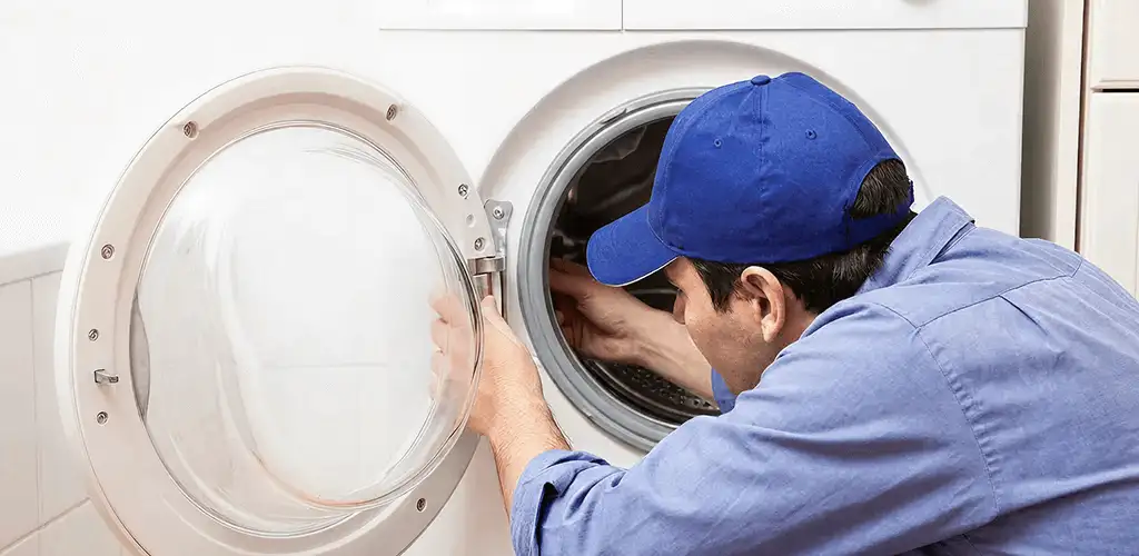 Washing machine repair handyman inspecting a front-load washer drum in Evansville, IN