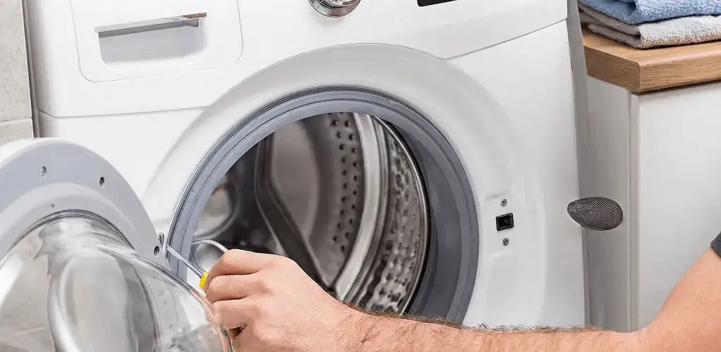 Handyman repairing a front-load washing machine and inspecting the drum in Evansville, IN