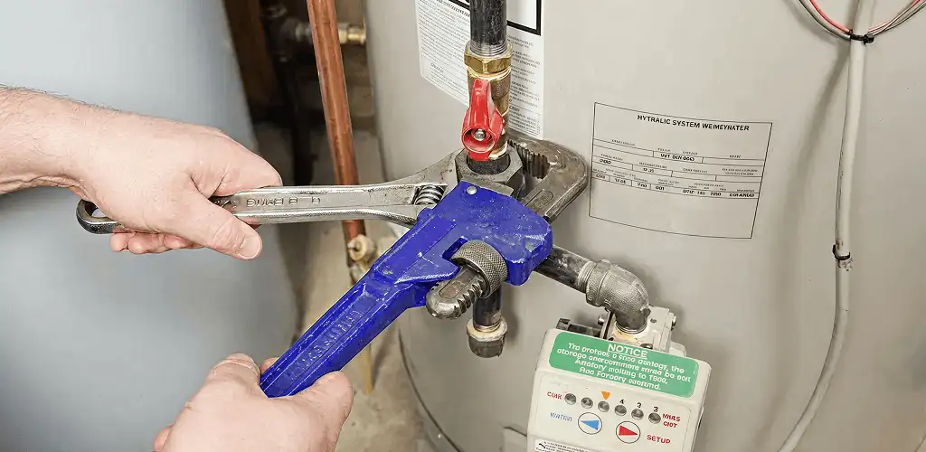 Water heater repair technician tightening the shutoff valve and supply line in Evansville, IN